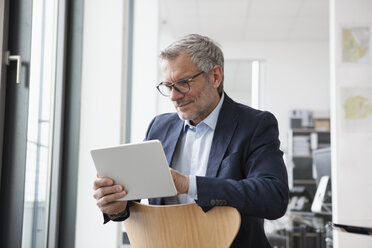 Successful businessman in his office using digital tablet - RBF004313