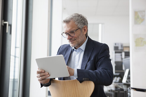 Erfolgreicher Geschäftsmann in seinem Büro mit digitalem Tablet - RBF004313