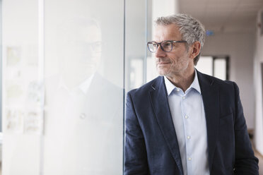 Erfolgreicher Geschäftsmann steht in seinem Büro und schaut aus dem Fenster - RBF004316