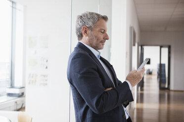 Erfolgreicher Geschäftsmann, der in seinem Büro ein digitales Tablet benutzt - RBF004317