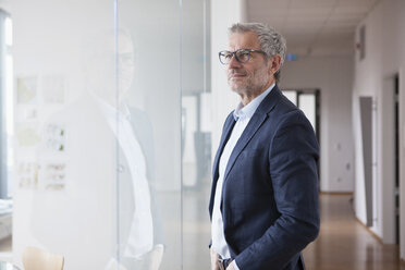 Erfolgreicher Geschäftsmann steht in seinem Büro und schaut aus dem Fenster - RBF004323