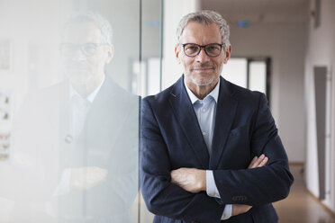 Successful businessman standing in his office with arms crossed - RBF004324