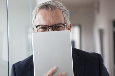 Erfolgreicher Geschäftsmann steht in seinem Büro und hält ein digitales Tablet, lizenzfreies Stockfoto