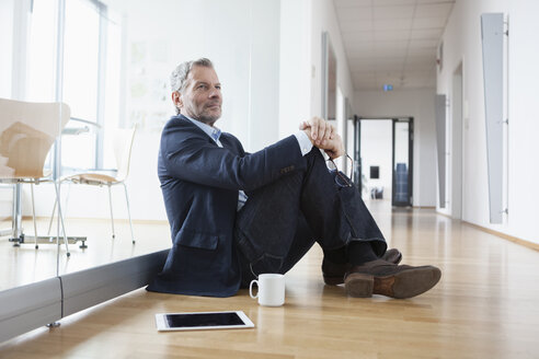 Erfolgreicher Geschäftsmann sitzt auf dem Boden und macht eine Pause - RBF004328