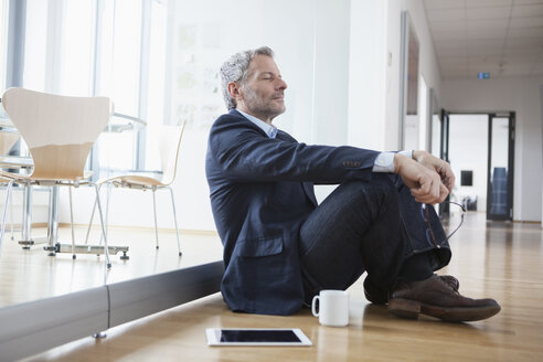 Successful businessman sitting on floor taking a break - RBF004329