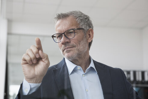 Erfolgreicher Geschäftsmann im Büro berührt den Glasbildschirm - RBF004332