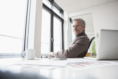 Mature man sitting relaxed in office stock photo