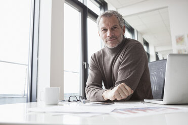 Mature man sitting in office using laptop - RBF004340