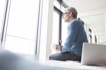 Reifer Mann sitzt entspannt im Büro - RBF004344