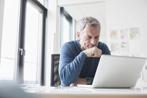 Mature man sitting in office using laptop - RBF004348