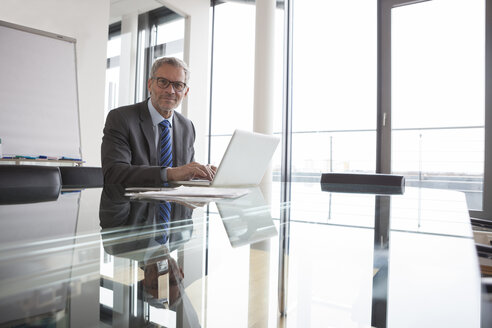 Älterer Manager sitzt im Büro und benutzt einen Laptop - RBF004355