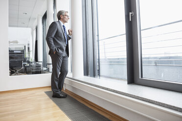 Erfolgreicher Manager im Büro, der durch ein Fenster schaut - RBF004365