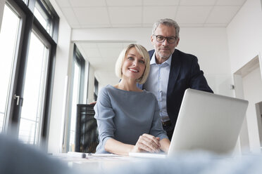 Geschäftsmann und Frau arbeiten zusammen im Büro an einem Laptop - RBF004377