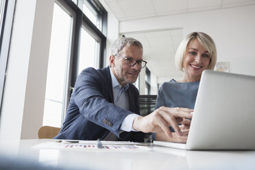 Geschäftsmann und Frau arbeiten zusammen im Büro an einem Laptop - RBF004378