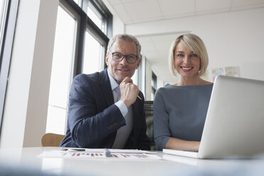 Geschäftsmann und Frau arbeiten zusammen im Büro an einem Laptop - RBF004379