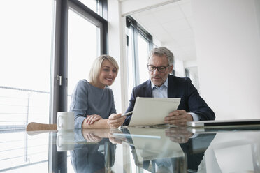 Businessman and woman working together in office discussing documents - RBF004383