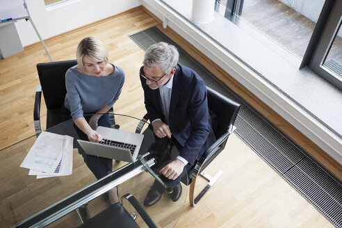 Geschäftsmann und Frau arbeiten zusammen im Büro an einem Laptop - RBF004387