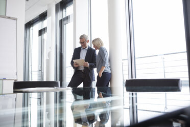 Businessman and woman in office looking at digital tablet - RBF004388