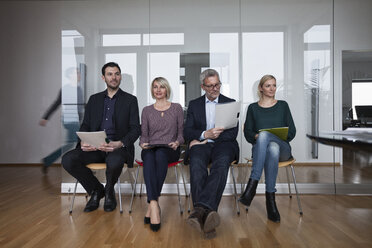 Four people sitting in a row, waiting in office - RBF004404