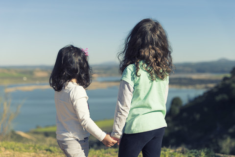 Spanien, Burujon, Rückenansicht von zwei kleinen Mädchen, die auf einen See schauen, lizenzfreies Stockfoto
