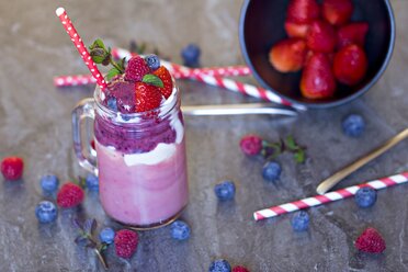 Smoothie with natural yoghurt, banana, strawberry, raspberry and blueberry in glass - YFF000535