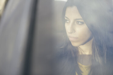 Porträt einer jungen Frau, die in einem Auto sitzt und durch ein Fenster schaut - ABZF000333