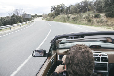 Man driving a convertible car on empty country road - ABZF000335