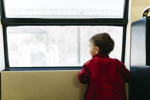 Back view of little boy on his first train ride looking through window stock photo