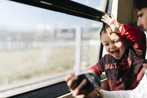 Glücklicher kleiner Junge auf seiner ersten Zugfahrt, der mit seiner Mutter Spaß hat - JRFF000536