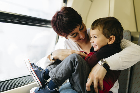 Glücklicher kleiner Junge auf seiner ersten Zugfahrt, der mit seiner Mutter Spaß hat, lizenzfreies Stockfoto