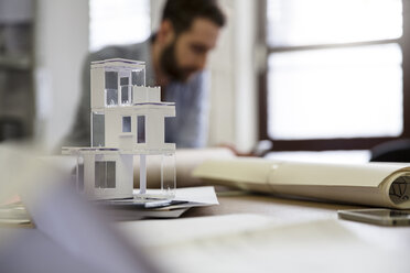 Desktop with architectural model and man in background - FKF001772