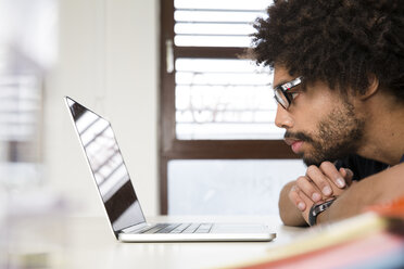 Kreativer Fachmann im Büro mit Blick auf den Laptop - FKF001788