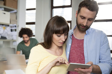 Zwei Kreativprofis teilen sich ein digitales Tablet im Büro - FKF001799