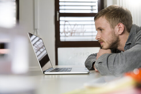 Kreativer Fachmann im Büro mit Blick auf den Laptop - FKF001820