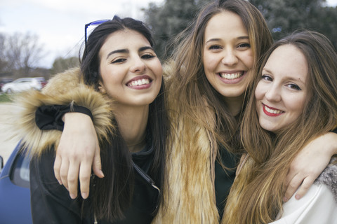 Gruppenbild von drei glücklichen jungen Frauen Arm in Arm, lizenzfreies Stockfoto