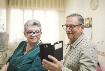 Senior couple looking at smartphone at home - EPF000067