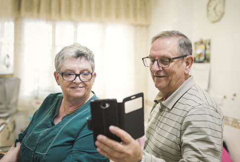 Älteres Paar schaut zu Hause auf sein Smartphone - EPF000067