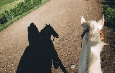 Peru, Cusco, shadow of woman riding horse on dirt road - GEMF000853