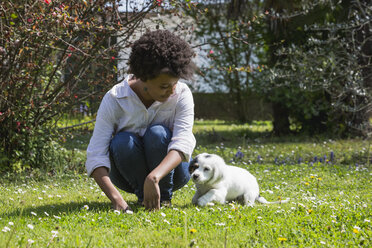 Junge Frau spielt mit ihrem Hund auf einer Wiese - MAUF000430