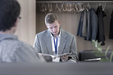Junger Mann liest Zeitschrift im Wartebereich eines Büros - SGF002013