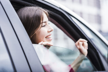 Brünette Frau sitzt im Auto und schaut durch das Fenster - UUF006854