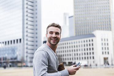 Young man in the city holding smartphone - UUF006864