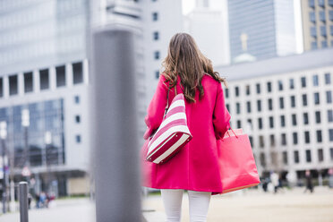 Junge Frau mit Einkaufstüten beim Spaziergang in der Stadt, Rückansicht - UUF006871