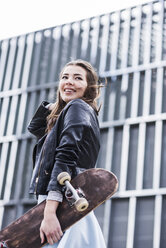 Junge Frau mit Skateboard in der Stadt - UUF006899