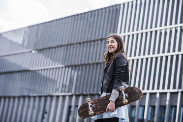 Junge Frau mit Skateboard in der Stadt - UUF006901