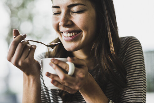 Junge Frau trinkt Cappuccino, löffelt Milchschaum - UUF006908