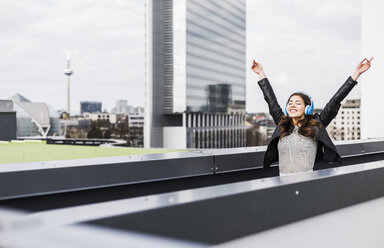 Young woman in the city wearing headphones, dancing - UUF006911