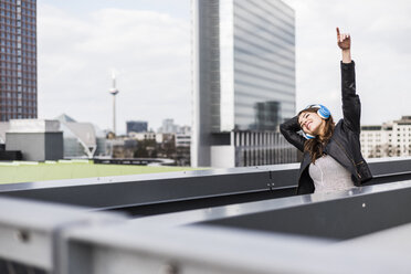 Young woman in the city wearing headphones, dancing - UUF006912