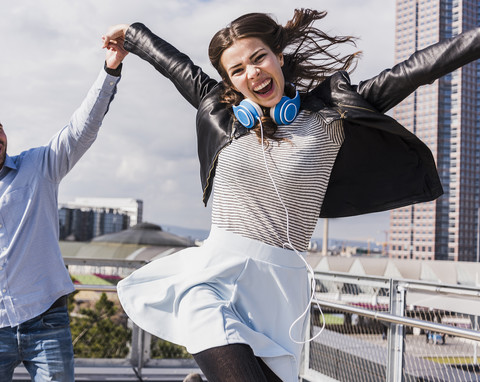 Young happy woman jumping and holding hands with friend stock photo