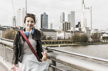 Junge Frau in der Stadt mit Einkaufstüten und Croissant - UUF006929